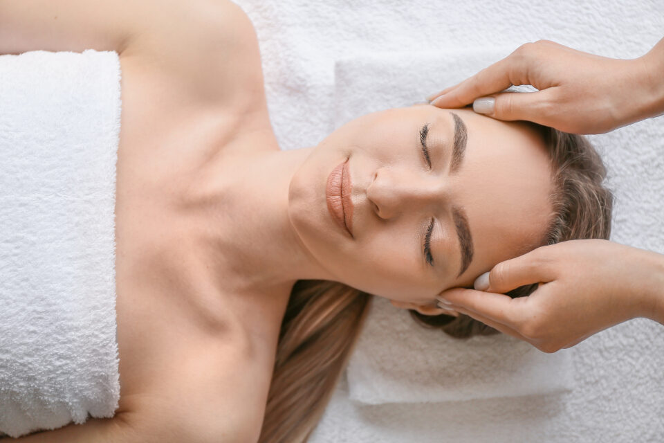 Esthetician giving a client a facial massage in a treatment room